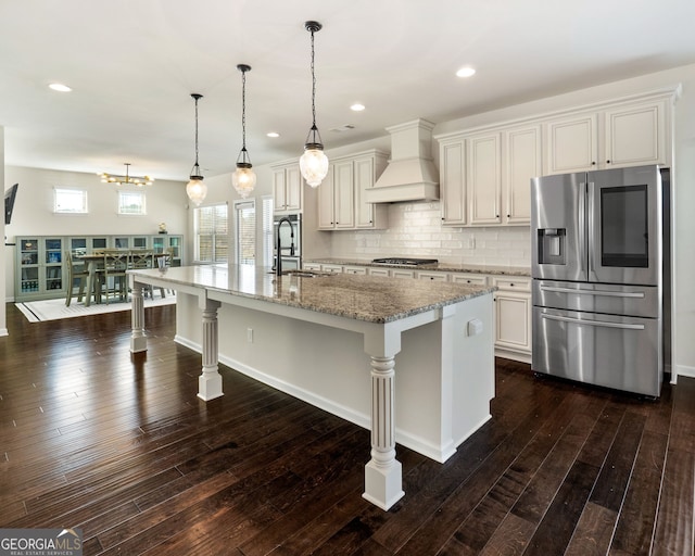 kitchen featuring appliances with stainless steel finishes, a kitchen island with sink, custom exhaust hood, a kitchen bar, and a sink