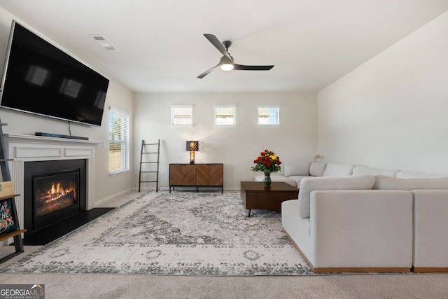 living room featuring a fireplace with flush hearth, visible vents, ceiling fan, and baseboards