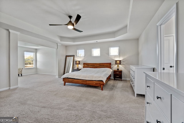 bedroom with light carpet, ceiling fan, baseboards, and a raised ceiling