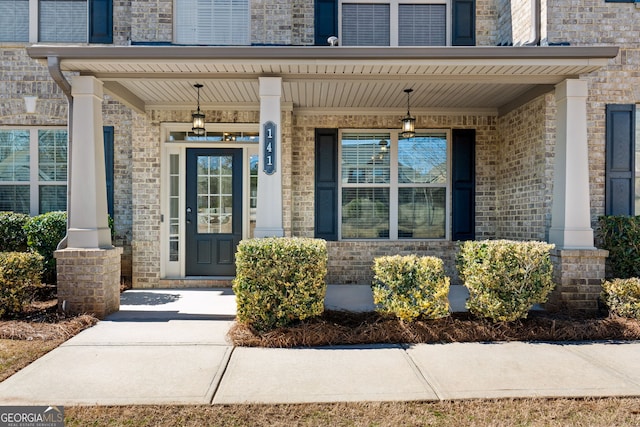 property entrance with a porch and brick siding