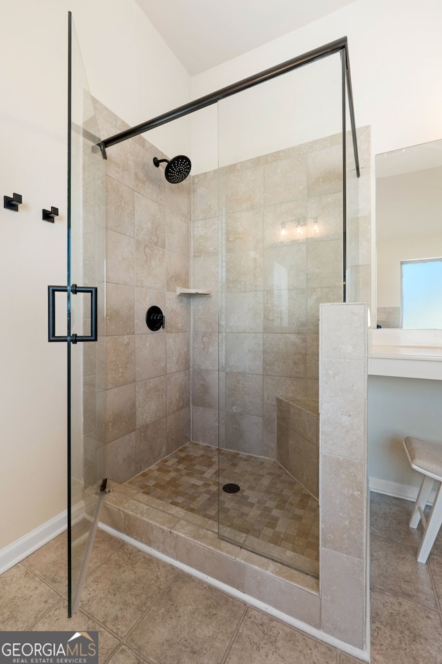 full bath with baseboards, a tile shower, and tile patterned floors