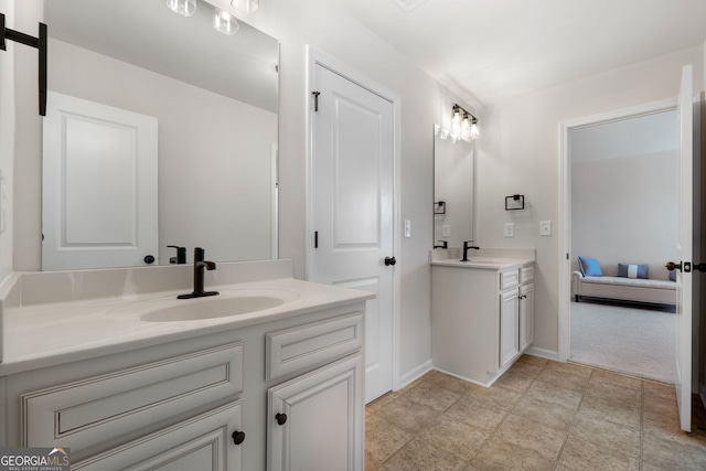 full bath with two vanities, a sink, and baseboards