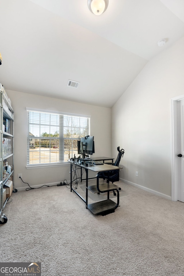 carpeted office space featuring baseboards, visible vents, and vaulted ceiling