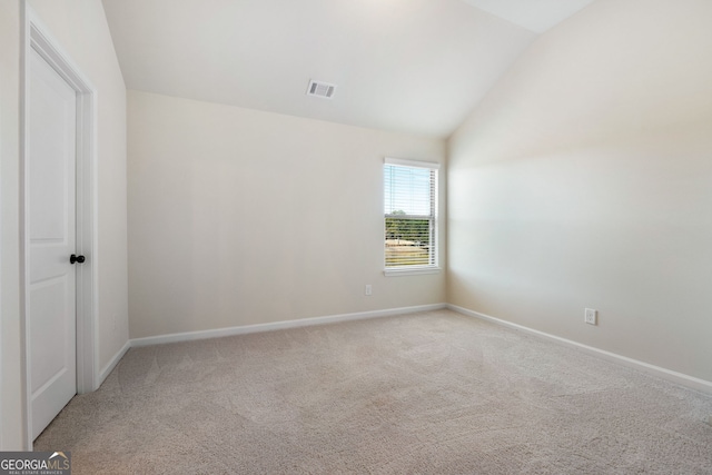 empty room featuring visible vents, vaulted ceiling, light carpet, and baseboards