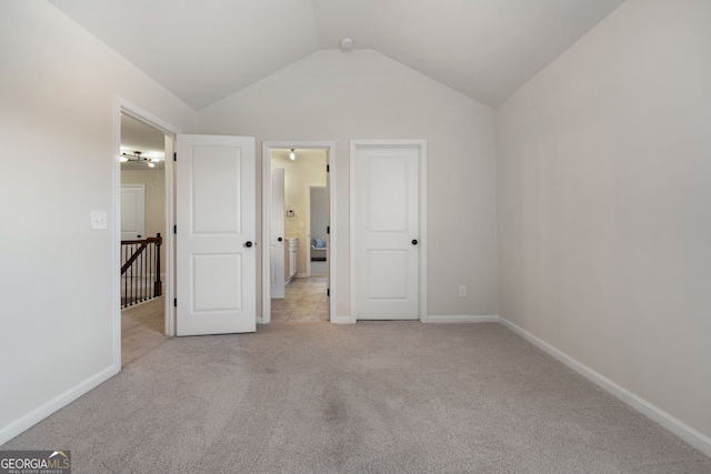 unfurnished bedroom featuring vaulted ceiling, baseboards, and light colored carpet