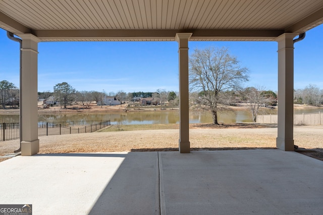 view of patio featuring a water view and fence