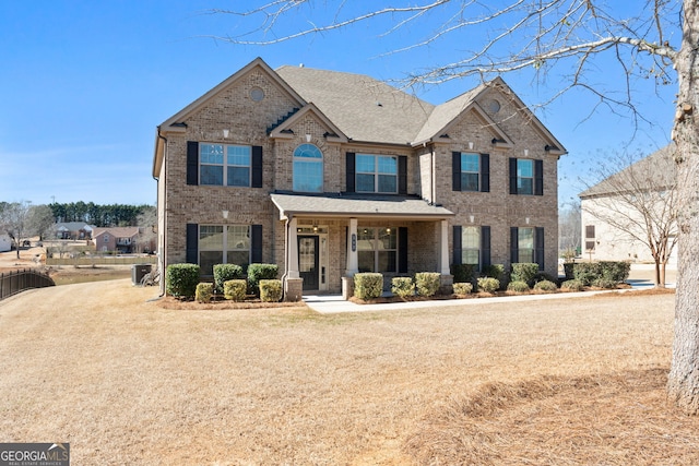 view of front facade featuring brick siding, a porch, and a shingled roof