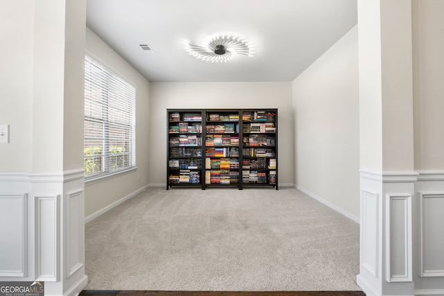 unfurnished room with light carpet, visible vents, and wainscoting