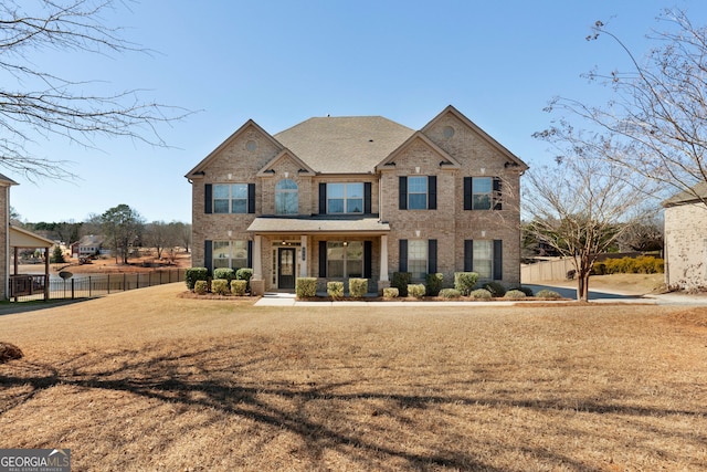 view of front of property featuring fence, a front lawn, and brick siding