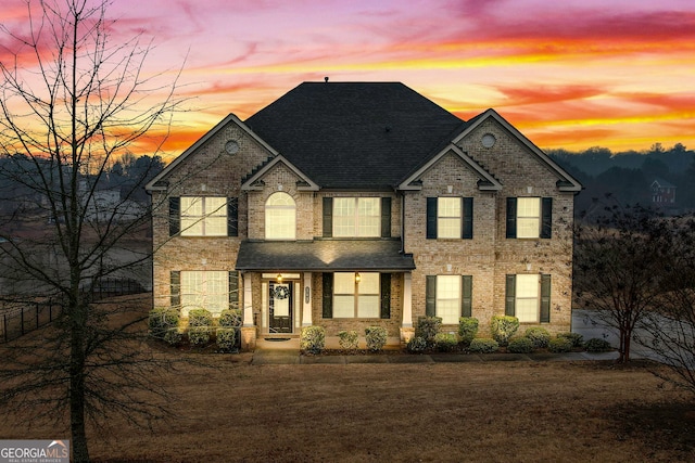 view of front of home featuring a front yard, brick siding, and roof with shingles