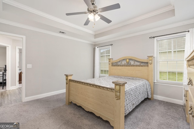 bedroom featuring baseboards, visible vents, light colored carpet, ornamental molding, and a tray ceiling