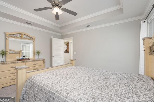 bedroom featuring ornamental molding, a raised ceiling, visible vents, and ceiling fan