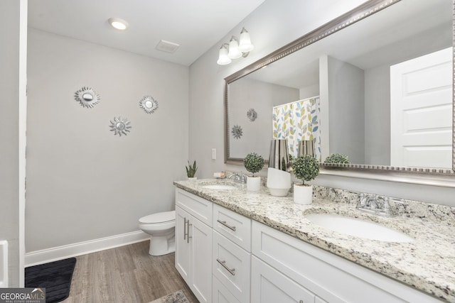 bathroom with toilet, baseboards, a sink, and wood finished floors