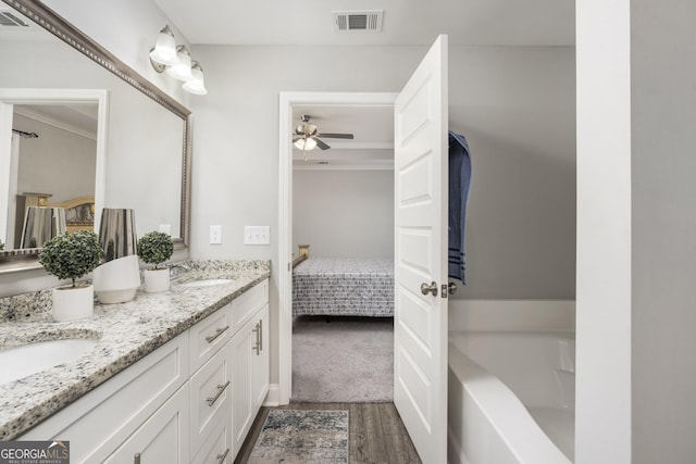 ensuite bathroom featuring double vanity, visible vents, wood finished floors, ensuite bathroom, and a sink