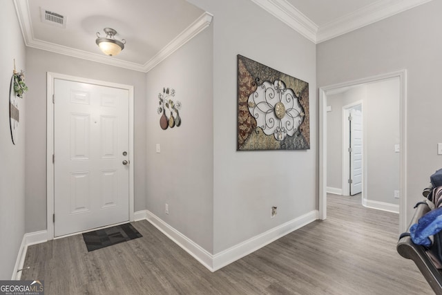 foyer entrance with ornamental molding, visible vents, baseboards, and wood finished floors