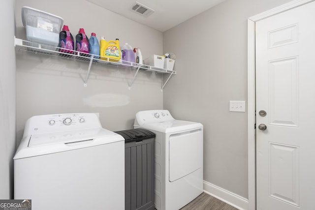 laundry area with washer and clothes dryer, visible vents, wood finished floors, laundry area, and baseboards