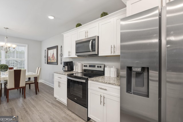 kitchen with light wood finished floors, hanging light fixtures, appliances with stainless steel finishes, white cabinetry, and light stone countertops