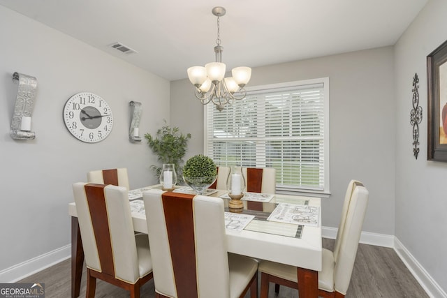 dining room with dark wood-style floors, baseboards, visible vents, and an inviting chandelier