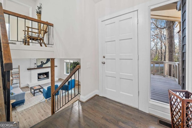 foyer featuring dark wood-type flooring, plenty of natural light, a fireplace, and visible vents