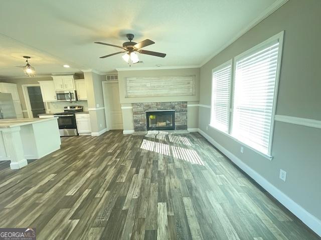 unfurnished living room featuring dark wood finished floors, a fireplace, crown molding, and baseboards