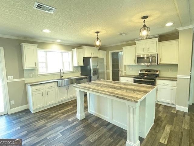 kitchen with visible vents, white cabinets, light countertops, appliances with stainless steel finishes, and hanging light fixtures