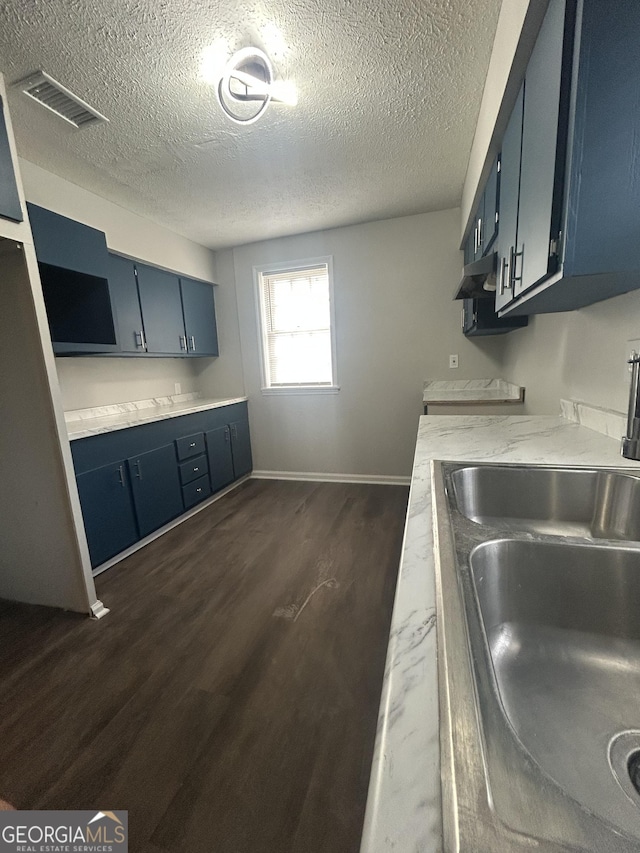 kitchen with blue cabinets, light countertops, a sink, and visible vents