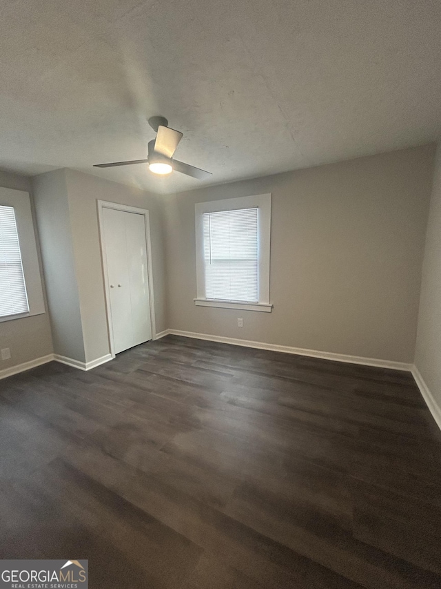 unfurnished bedroom featuring dark wood-style floors, ceiling fan, and baseboards