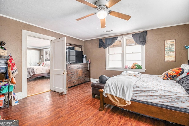 bedroom with visible vents, a ceiling fan, wood finished floors, crown molding, and baseboards