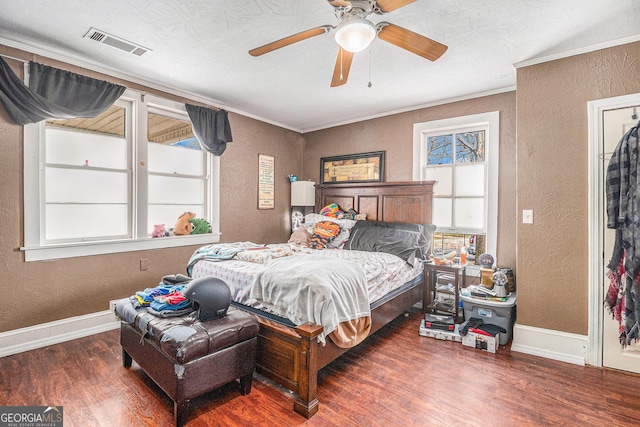 bedroom featuring visible vents, wood finished floors, crown molding, baseboards, and a textured wall