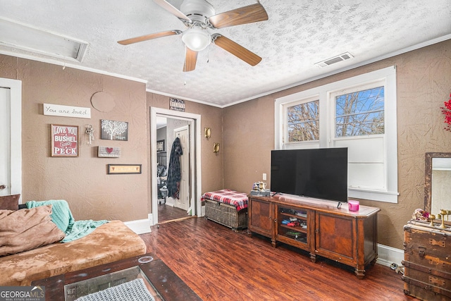 living room with visible vents, a textured ceiling, wood finished floors, crown molding, and a textured wall