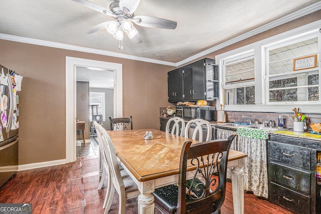 dining room featuring baseboards, dark wood finished floors, a ceiling fan, and ornamental molding