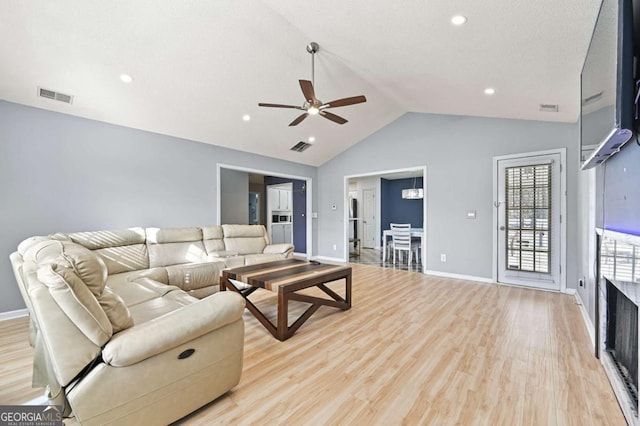 living room featuring lofted ceiling, light wood finished floors, baseboards, and visible vents