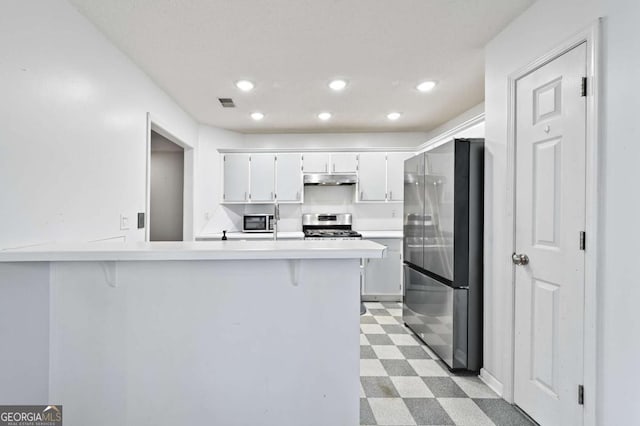 kitchen with under cabinet range hood, white cabinetry, light countertops, appliances with stainless steel finishes, and light floors