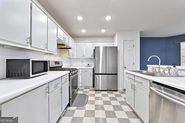 kitchen featuring light floors, light countertops, appliances with stainless steel finishes, a sink, and under cabinet range hood