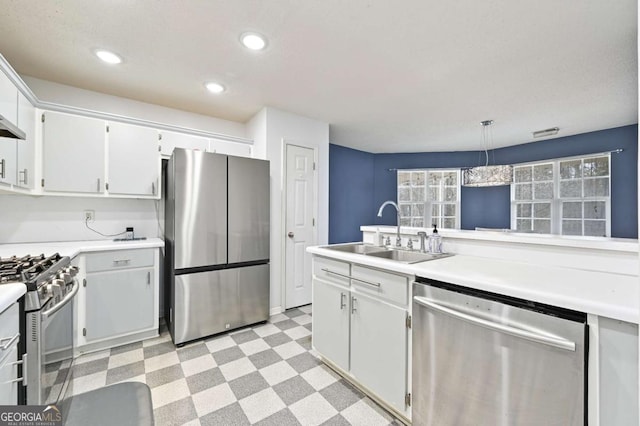 kitchen with appliances with stainless steel finishes, hanging light fixtures, light countertops, light floors, and a sink