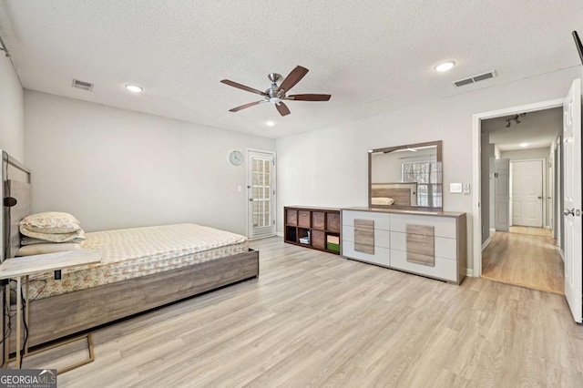 bedroom featuring access to exterior, visible vents, light wood-style flooring, and a textured ceiling