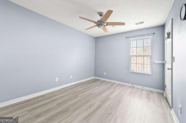 empty room featuring light wood finished floors, visible vents, ceiling fan, a textured ceiling, and baseboards