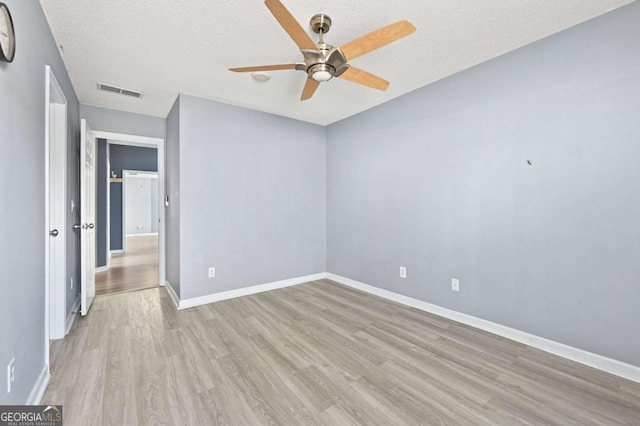 unfurnished bedroom featuring light wood finished floors, visible vents, a ceiling fan, a textured ceiling, and baseboards