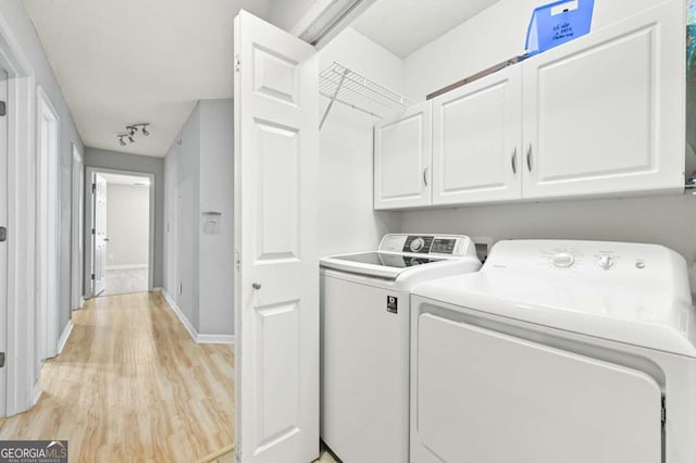 laundry room featuring cabinet space, baseboards, light wood finished floors, and washer and dryer