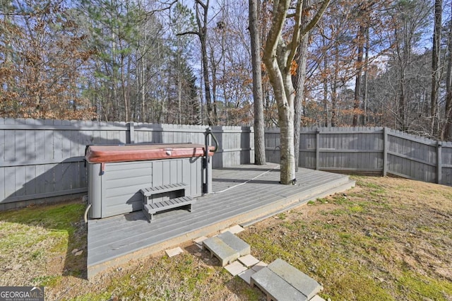 deck with a fenced backyard, a yard, and a hot tub