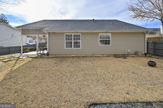 rear view of property with a patio, a yard, a shingled roof, and a fenced backyard