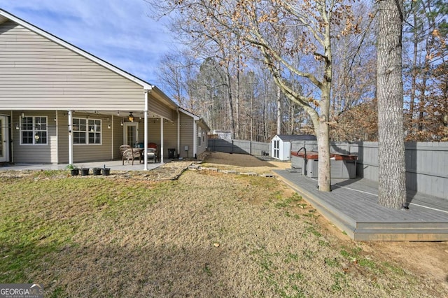 view of yard featuring a storage unit, a patio area, a fenced backyard, a jacuzzi, and an outdoor structure