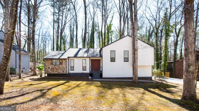 tri-level home with stone siding and a front lawn