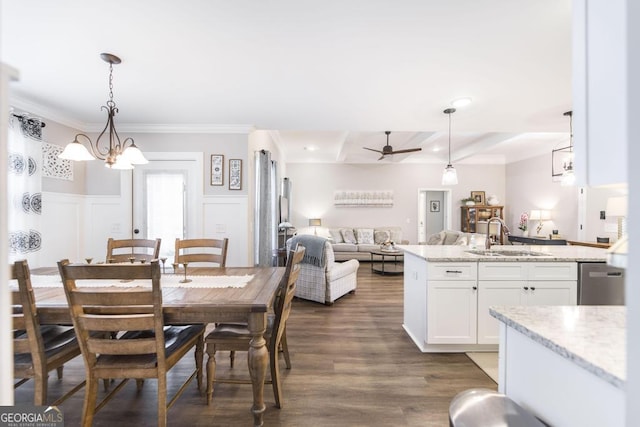 dining room with dark wood-style flooring, a wainscoted wall, crown molding, a decorative wall, and ceiling fan with notable chandelier