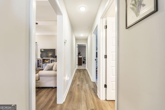 corridor with light wood-type flooring and baseboards