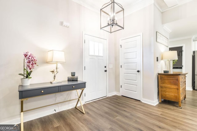 entrance foyer featuring a chandelier, crown molding, baseboards, and wood finished floors