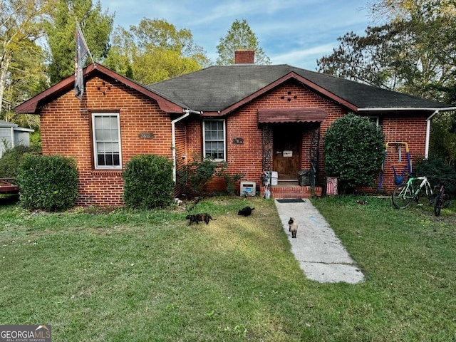 ranch-style home with a front yard, brick siding, and a chimney