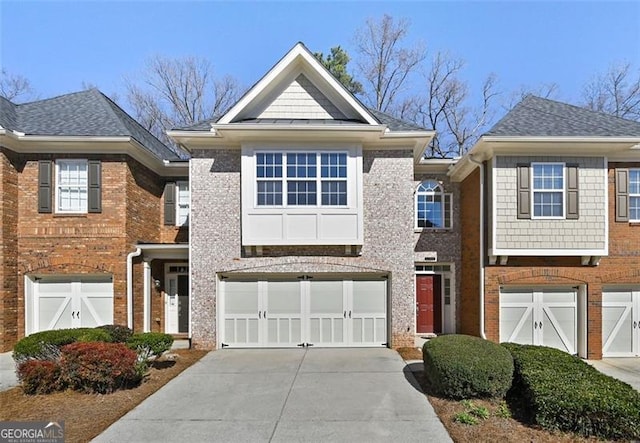 view of front of home featuring driveway, an attached garage, a shingled roof, and brick siding