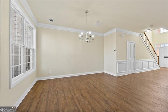 empty room with ornamental molding, wood finished floors, and an inviting chandelier