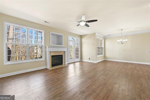 unfurnished living room with ceiling fan with notable chandelier, a fireplace with flush hearth, visible vents, baseboards, and dark wood finished floors